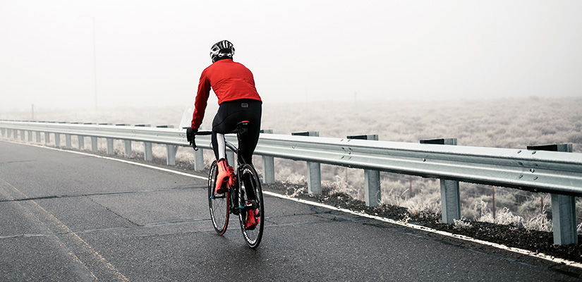 This cyclist is riding outdoors in Winter. When doing a winter cycling training plan outdoors, its essential to have the right clothing.