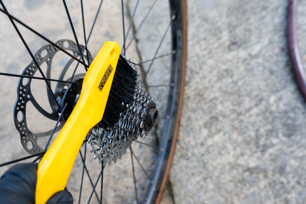 A brush is used to scrub the cassette of a bike.