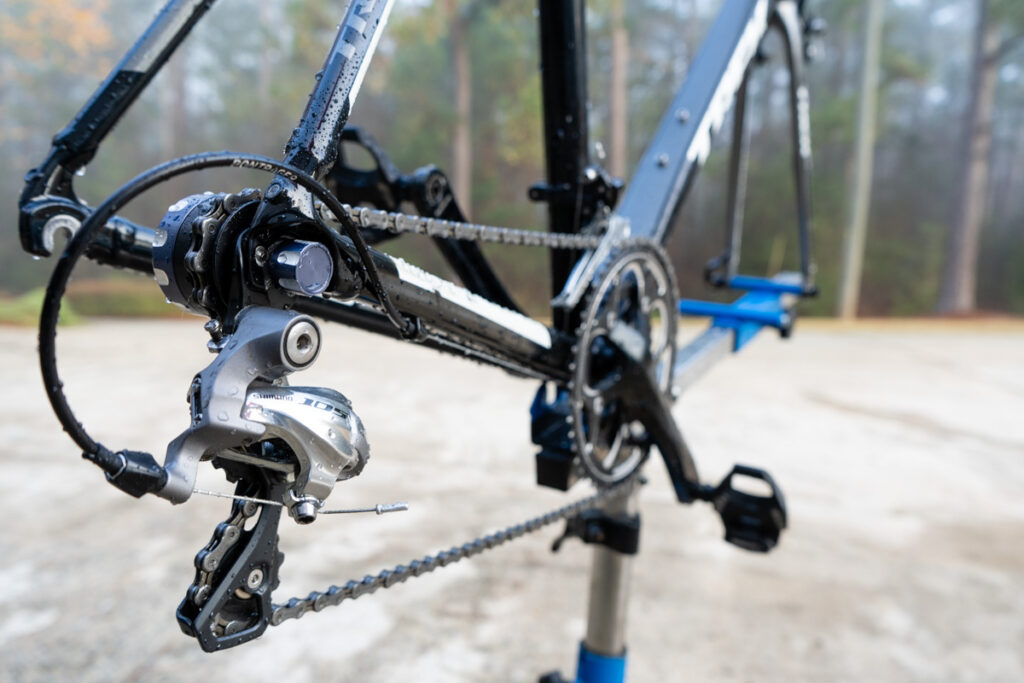 A bike is on a work stand with the rear wheel removed. The bike is prepared to clean and lube a chain.