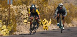 Person cycling fast on a flat desert road.